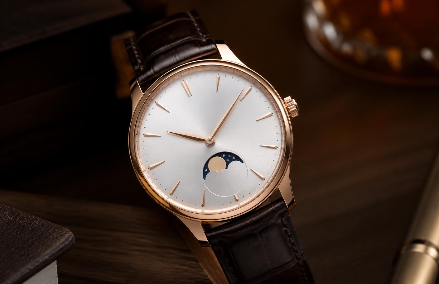 Reloj mecánico en acabado oro rosa con esfera blanco plata y correa de piel marrón sobre una mesa de nogal